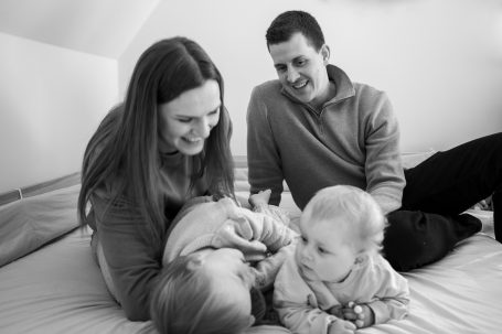 Eine Familie spielt gemeinsam auf einem Bett, dabei lachen sie und genießen die Zeit.