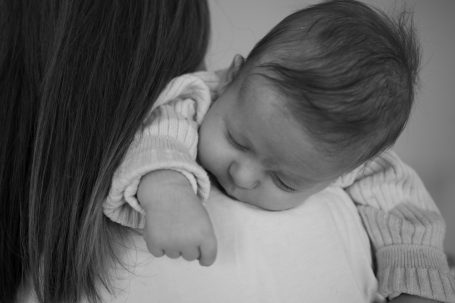 Ein schlafendes Baby liegt auf der Schulter einer Person.